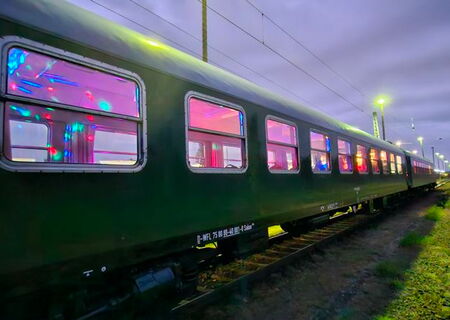 Außenansicht eines historischen Salonwagens in Abendstimmung und farbigen Partylichtern innen