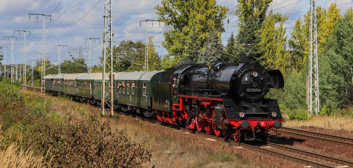 WFL Dampflok fahrt durch sommerliche Landschaft. Aus den Wagen winken Fahrgäste.
