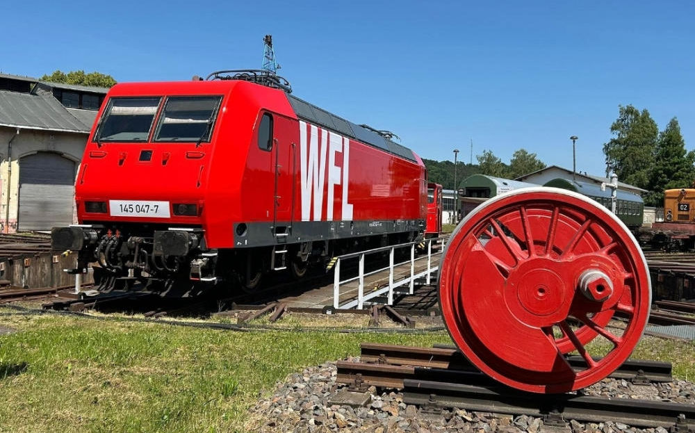 rote Elektrolokomotive steht auf Drehscheibe vor den Lokschuppen des Heimat Betriebswerk Nossen. Drehscheibe ist eine Einrichtung zum horizontalen Drehen von Schienenfahrzeugen zum Anschlussgleis.